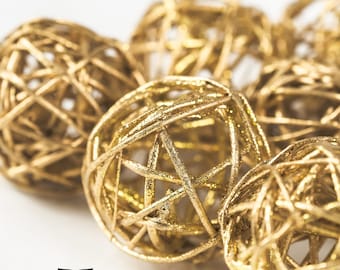 Könnte beinhalten: Eine Gruppe von goldfarbenen, geflochtenen Kugel-Ornamenten. Die Kugeln bestehen aus dünnen, miteinander verflochtenen Drahtsträngen, die ein zartes und luftiges Aussehen erzeugen.