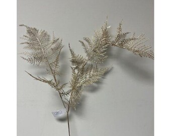 Peut inclure: Une tige de fougère artificielle décorative avec des feuilles argentées délicates. La fougère a une apparence naturaliste et est placée sur un fond clair et uni. Une petite étiquette est attachée à la tige.