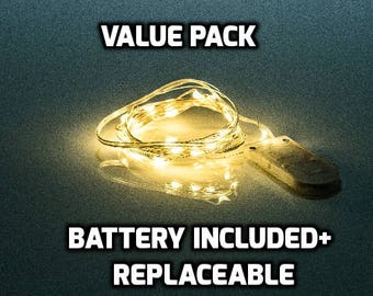 Puede incluir: Una cadena de luces LED blanco cálido con un paquete de baterías. La imagen incluye el texto "VALUE PACK" y "BATTERY INCLUDED+ REPLACEABLE". Las luces están enrolladas e iluminadas sobre un fondo oscuro.