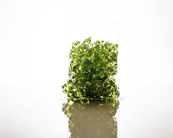 May include: A clear plastic bag filled with green glass gems. The gems are in a pile and are reflecting light.