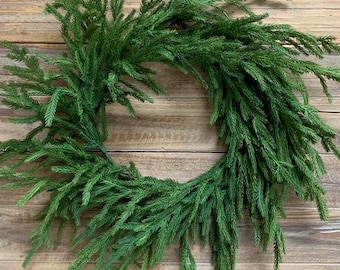 Könnte beinhalten: Ein grüner künstlicher Kiefernkranz, perfekt zum Dekorieren für die Feiertage. Der Kranz besteht aus realistisch aussehenden Kiefernästen und ist ideal, um jedem Raum einen Hauch von Grün zu verleihen.
