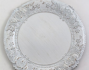 May include: White charger plate with an ornate, embossed design around the edge. The plate is made of a durable material and has a distressed, vintage look.