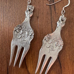 May include: A set of three ceramic mugs with a speckled, matte finish. The mugs are in shades of cream, light gray, and dark gray. Each mug has a simple, minimalist design and a rounded handle.