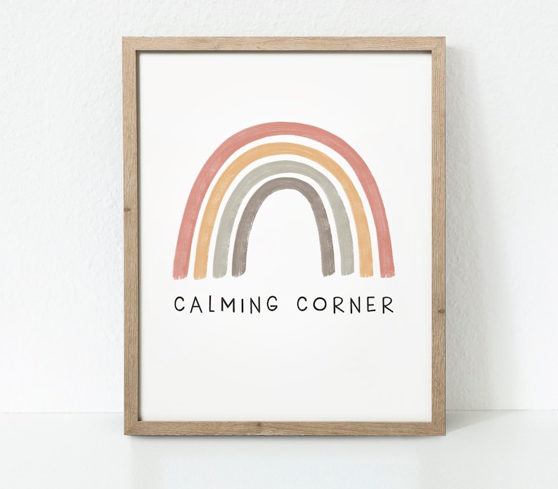 May include: A framed print with a rainbow in shades of pink, orange, yellow, gray, and brown. The rainbow is painted in a watercolor style. The text "CALMING CORNER" is printed below the rainbow.
