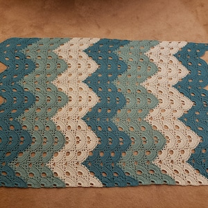 May include: A crocheted blanket with a chevron pattern in shades of teal, green, and white.