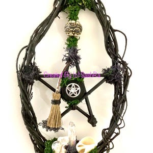 May include: A dark, rustic pentagram-shaped wall hanging. The design incorporates a woven vine frame, a central star, a small broom, and decorative elements like a crystal, shell, and moss. The text "Created By (c) SashRa" is visible.