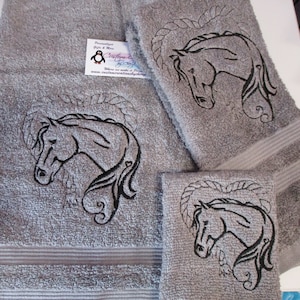 May include: Set of three gray towels with embroidered horse head designs. The towels are different sizes and have a soft, fluffy texture.