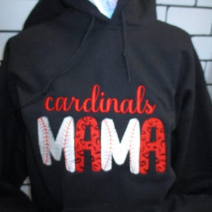 May include: Black hooded sweatshirt with the words "cardinals MAMA" embroidered in red and white. The word "cardinals" is in a script font, and the word "MAMA" has baseball stitching.