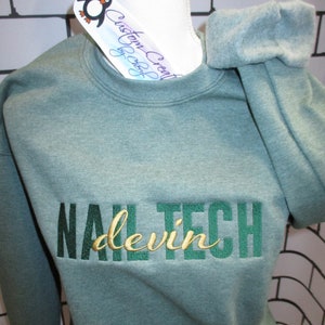 May include: A green sweatshirt with the text "NAIL TECH devin" embroidered in green and gold.
