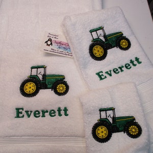 May include: Two white towels with green and yellow embroidered tractors and the name Everett. The towels are personalized gifts.
