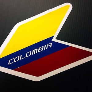 May include: A white arrow-shaped sticker with a yellow, blue, and red design. The word "COLOMBIA" is written in white letters on the blue stripe.