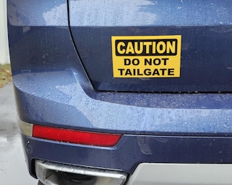 May include: A blue car with a yellow caution sign that reads "CAUTION DO NOT TAILGATE".