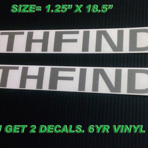 May include: Two white Pathfinder decals, each measuring 1.25 inches by 18.5 inches. The decals feature gray text and a design with black, gray, and red stripes. The text "PATHFINDER" is prominently displayed.