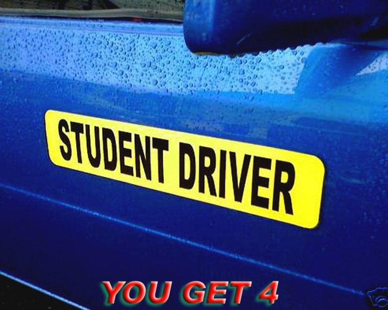 May include: A yellow and black sign with the text "STUDENT DRIVER" on a blue car. The sign is attached to the back of the car.