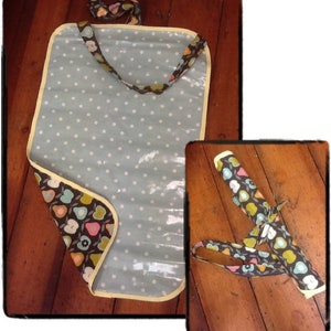 May include: A blue and white polka dot changing mat with a floral print border. The mat is rolled up and secured with a strap. The strap is made of the same floral fabric as the border.