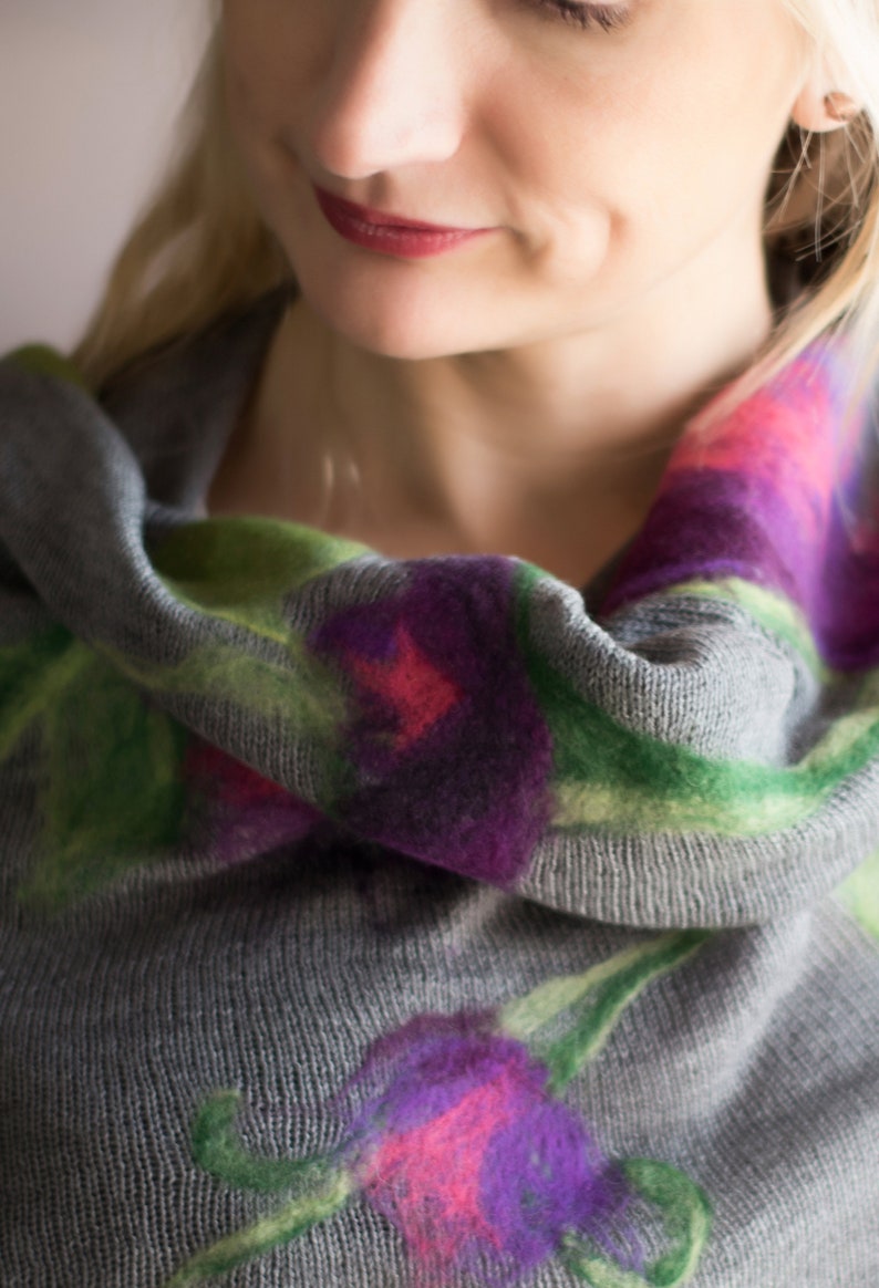 May include: A gray cowl neck sweater with a floral pattern in shades of green, purple, and pink.