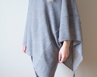May include: A grey knitted poncho with a cowl neck and a slightly asymmetrical hemline.