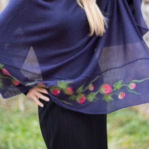May include: A navy blue shawl with a floral design featuring pink flowers and green leaves. The shawl is made of a soft, lightweight fabric and is perfect for layering.