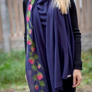 May include: A navy blue scarf with a floral design featuring pink roses and green leaves. The scarf is made of a soft, lightweight material and is perfect for adding a touch of elegance to any outfit.