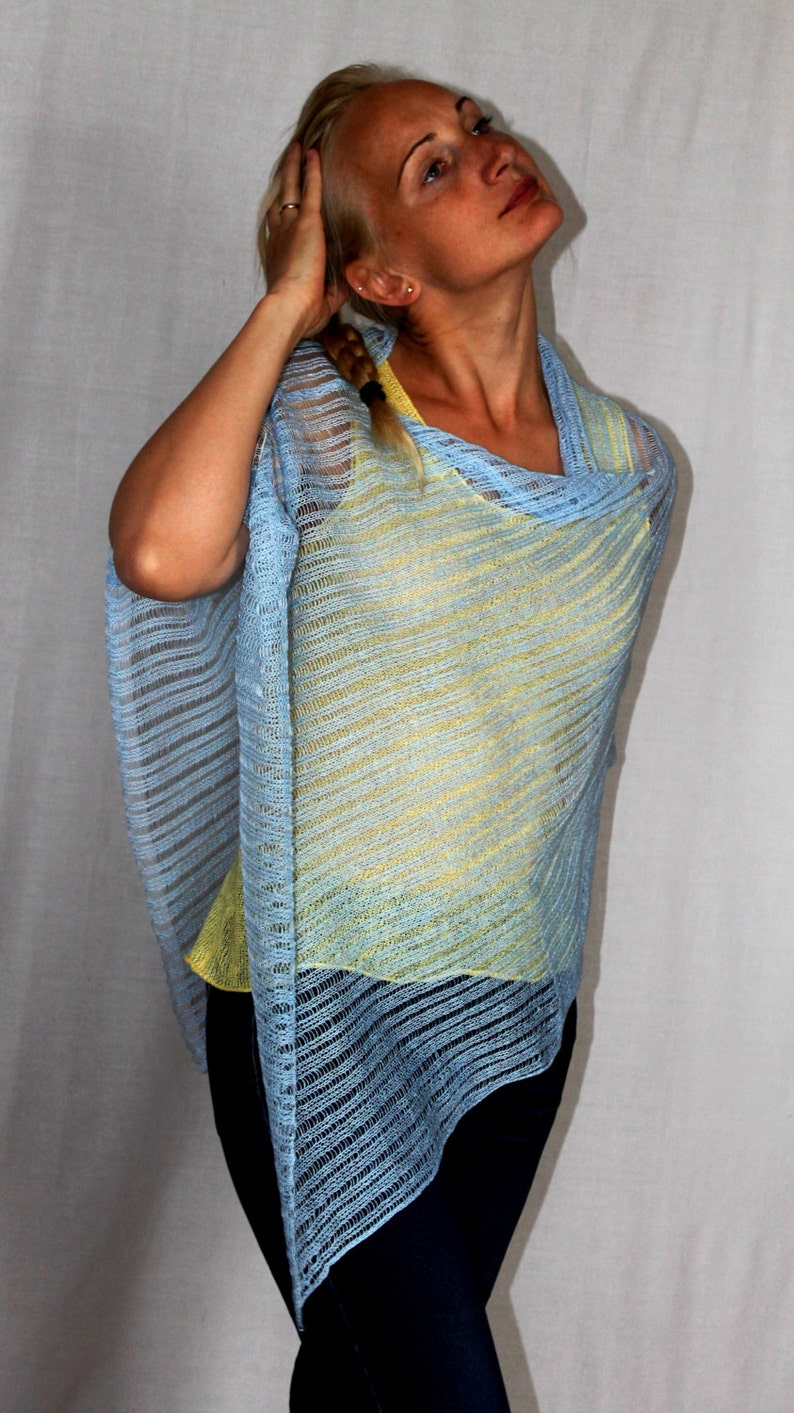 May include: A light blue and yellow striped knit poncho with a loose fit. The poncho is made of a lightweight, airy fabric.