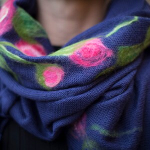 May include: A blue knitted scarf with pink and green floral embroidery.