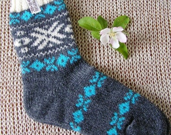 May include: A gray and white wool sock with a blue and white geometric pattern. The sock has a white tag that says "Eco Texture" on it.