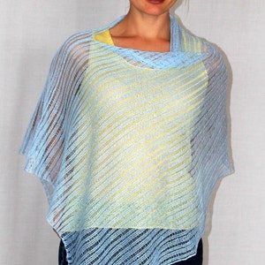 May include: A light blue knitted poncho with a yellow under layer. The poncho has a loose fit and a diagonal pattern.