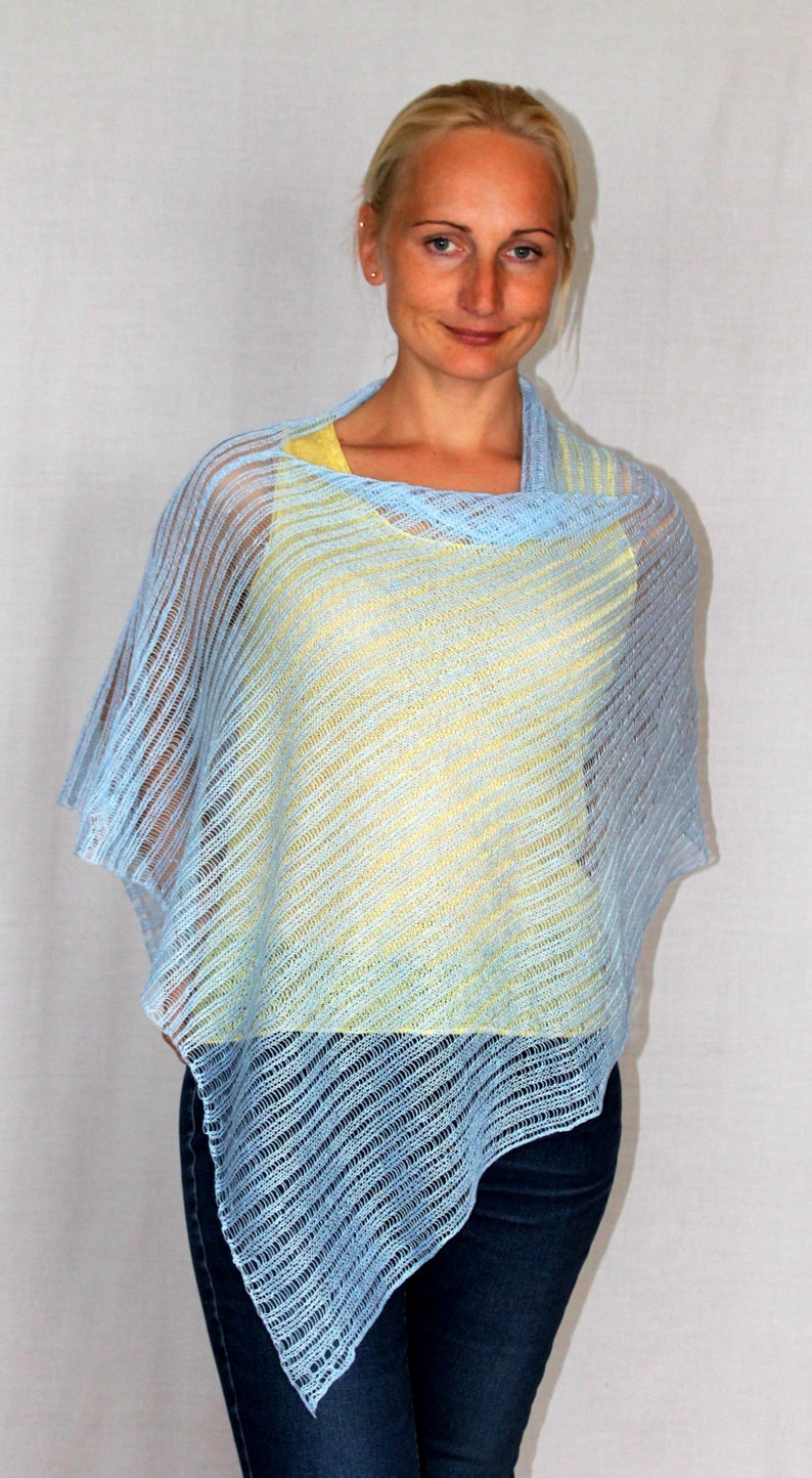 May include: A light blue knitted poncho with a yellow under layer. The poncho has a loose fit and a diagonal pattern.