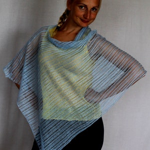 May include: A light blue knitted poncho with a yellow and blue striped pattern. The poncho is worn over a yellow tank top and black pants.