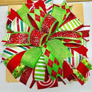May include: A large, multi-colored Christmas bow made of red, green, and white ribbon. The bow is tied in a knot and has a variety of patterns, including polka dots, stripes, and diamonds.