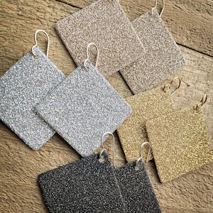 May include: A set of six square-shaped earrings with glitter finishes. The earrings are in silver, gold, black, and champagne colors.