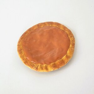 May include: A round, crispy cookie with a sweet, orange-colored filling. The cookie is slightly browned around the edges.