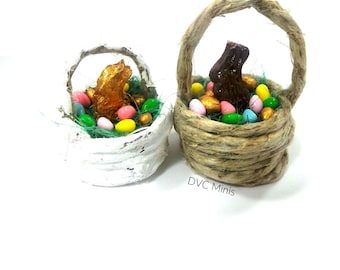 May include: Two miniature Easter baskets filled with colorful candy eggs and chocolate bunnies. One basket is white with a gold bunny, the other is brown with a brown bunny.  DVC Minis.