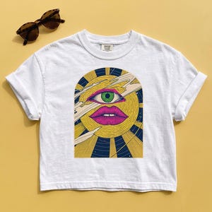 Psychedelic crop top in white cotton, third eye sun face in gold and magenta on a navy arch background