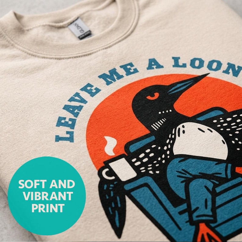 Close-up of Leave Me A Loon sweatshirt graphic in sand, soft and vibrant DTG print detail on cozy loon crewneck, retro bird gift for camping and cabin lovers