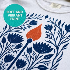 Detailed shot of soft and vibrant print quality of a White Comfort Colors boxy crop tee featuring a bold folk art botanical illustration of a lit match with red-orange flame surrounded by wildflowers, reading Hope Is A Small Rebellion — feminist liberal graphic crop top.