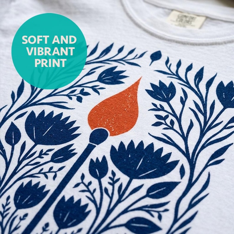 Detailed shot of soft and vibrant print quality of a White Comfort Colors boxy crop tee featuring a bold folk art botanical illustration of a lit match with red-orange flame surrounded by wildflowers, reading Hope Is A Small Rebellion — feminist liberal graphic crop top.