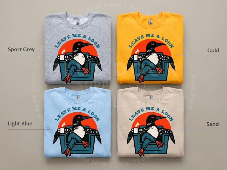 May include: Four crewneck sweatshirts in sport grey, gold, light blue, and sand colors. Each features a graphic of a loon sitting in a chair with a coffee mug, wearing blue jeans, and the text LEAVE ME A LOON printed in a circular arc above.