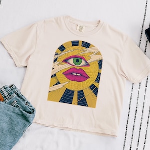 Lay Flat Celestial crop top in ivory Comfort Colors cotton, block print sun face with a third eye surrounded by rays and stars