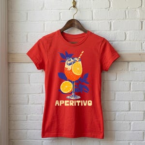 Aperitivo Italian summer tee in red on hanger — women's fitted graphic shirt with bold vintage spritz cocktail design, orange and blue linocut illustration