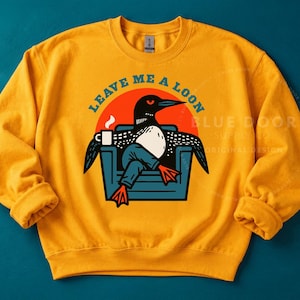 Loon sweatshirt in gold on teal background, funny bird watcher gift crewneck featuring a retro loon lounging with coffee, Comfort Colors style lake apparel