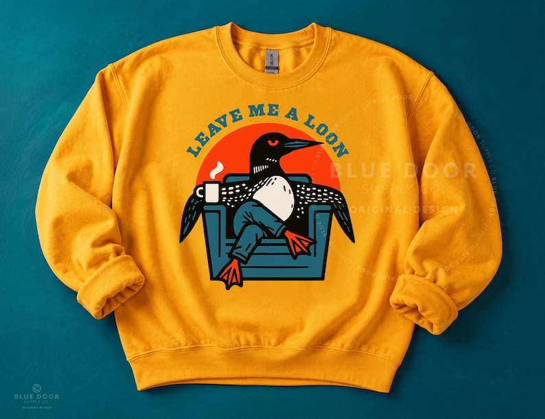 Loon sweatshirt in gold on teal background, funny bird watcher gift crewneck featuring a retro loon lounging with coffee, Comfort Colors style lake apparel