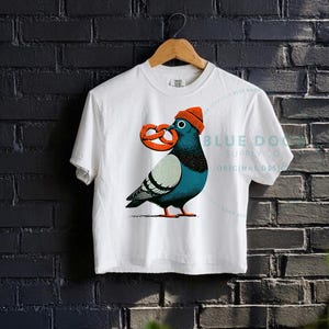 City bird crop in white against a dark brick wall, dopey pigeon in an orange knit beanie