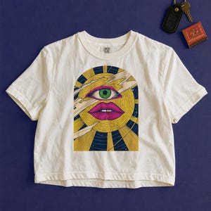 Trippy cropped graphic tee in white, celestial block print sun with an open eye, rays and comet streaks
