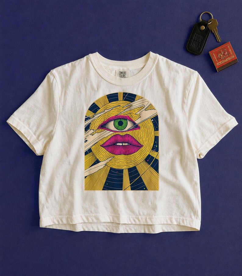 Trippy cropped graphic tee in white, celestial block print sun with an open eye, rays and comet streaks