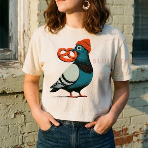 Boxy crop tee worn with jeans against a brick wall, ivory pigeon crop shown candid at 35mm depth of field