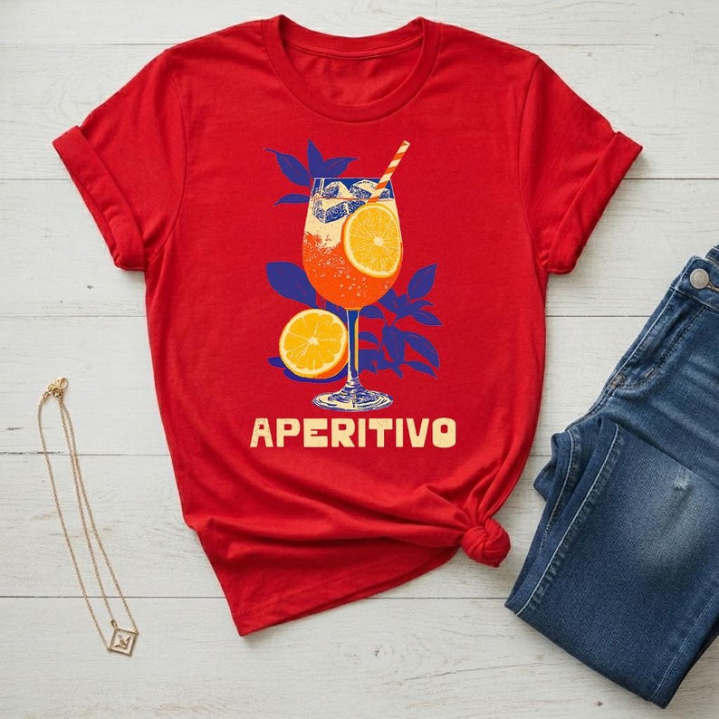 Aperitivo spritz shirt flat lay in red styled with denim and gold necklace — women's Italian summer graphic tee, cocktail lover gift, semi-fitted silhouette