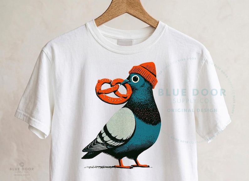 New York crop top in white on a wood hanger, city pigeon block print with correct blue-gray coloring