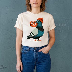 Comfort Colors tee in ivory worn with jeans, a relaxed unisex pigeon shirt shown candid at 35mm depth of field
