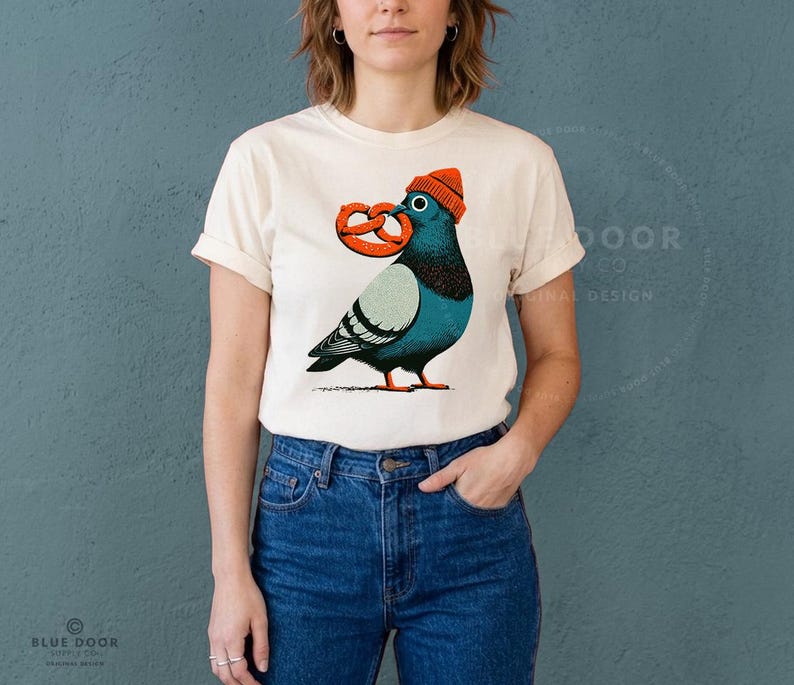 Comfort Colors tee in ivory worn with jeans, a relaxed unisex pigeon shirt shown candid at 35mm depth of field